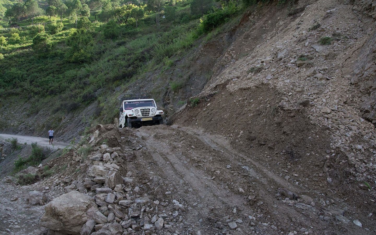 Landslide debris covering a mountain road beside a steep slope