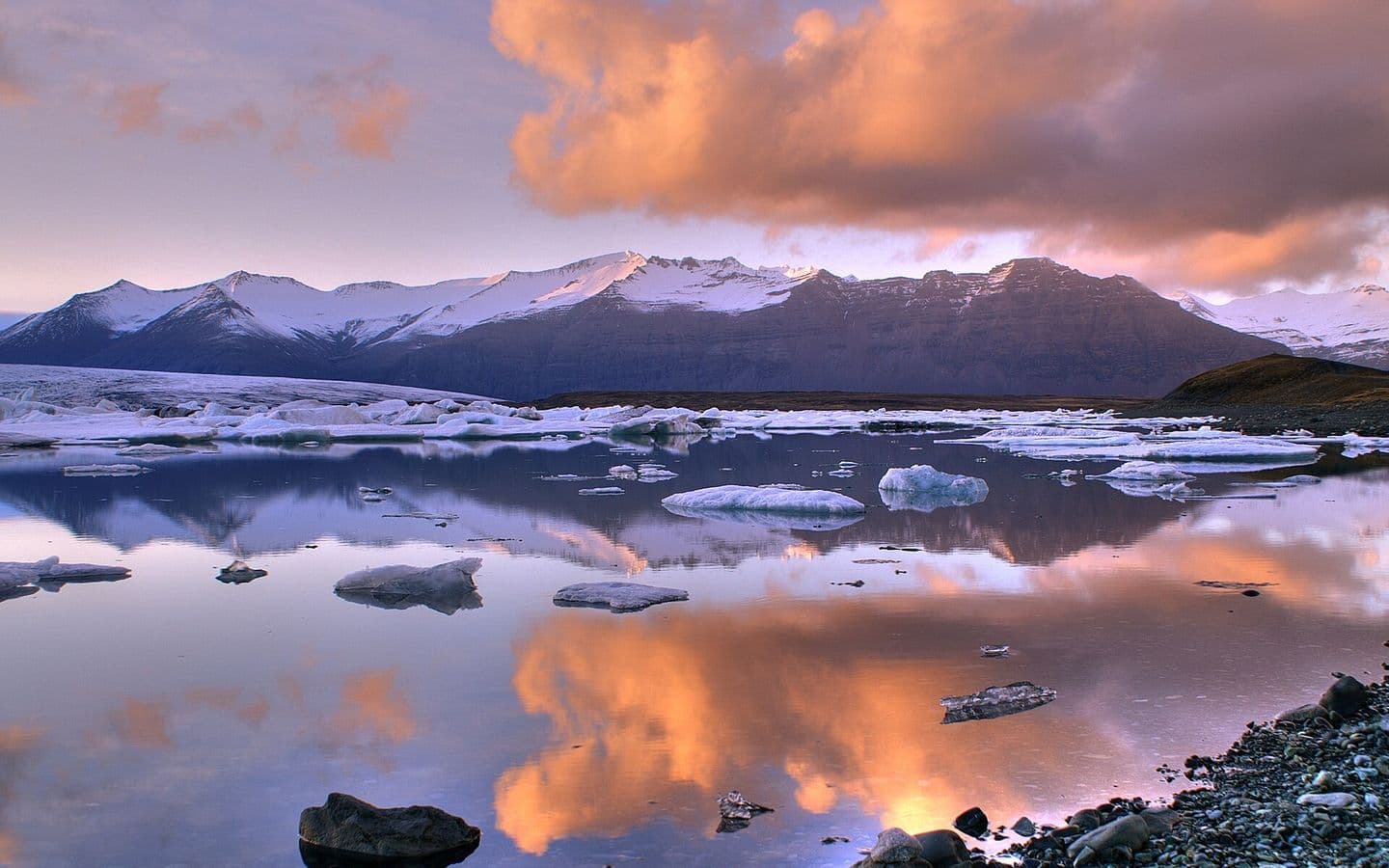 Glacial lake with icebergs below snow-covered mountains